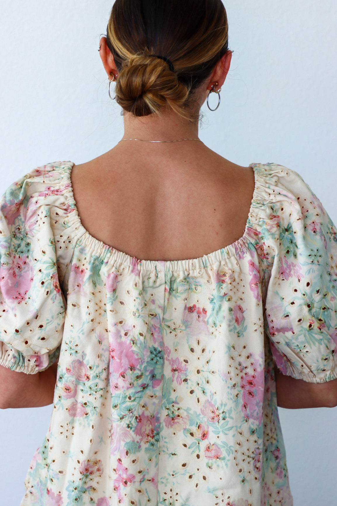Back view of a person wearing a floral blouse against a light background