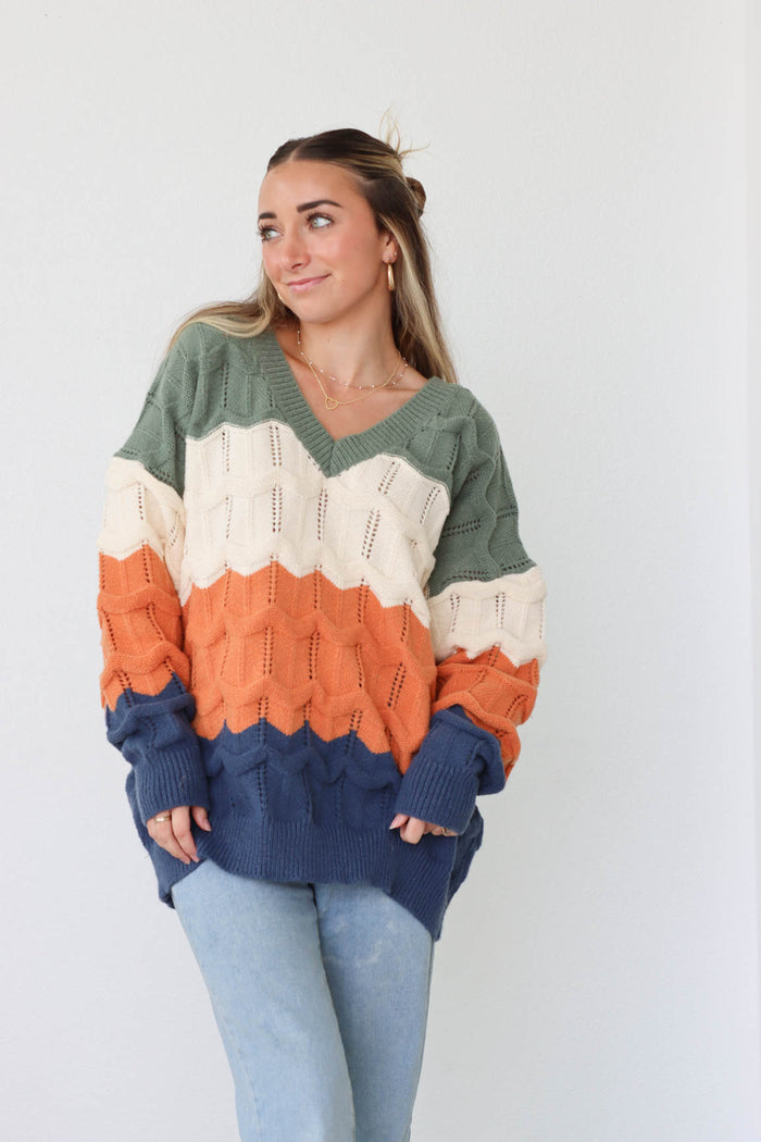 girl wearing green, cream, orange, and navy knit v-neck sweater