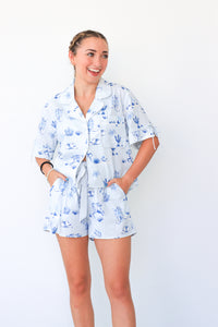 Woman wearing a light blue pajama set with floral pattern on a white background