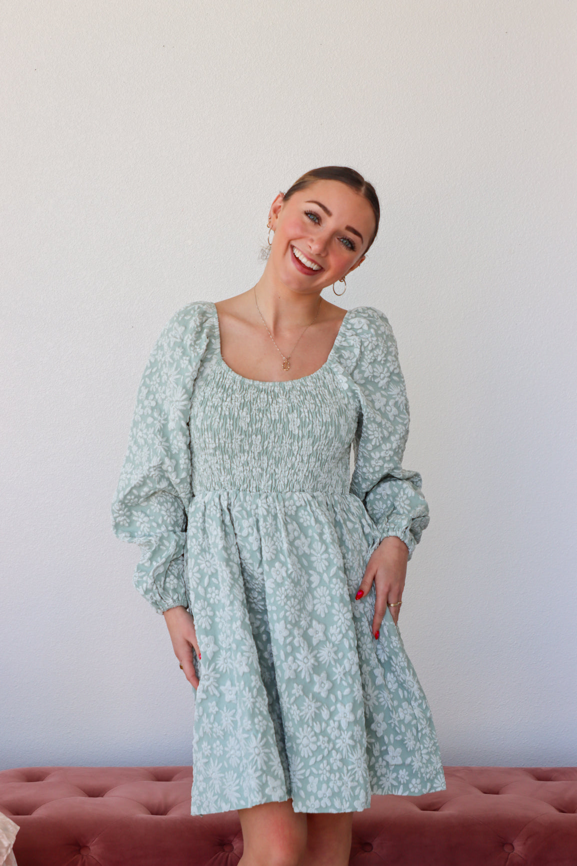 Woman wearing a light blue floral dress against a plain background