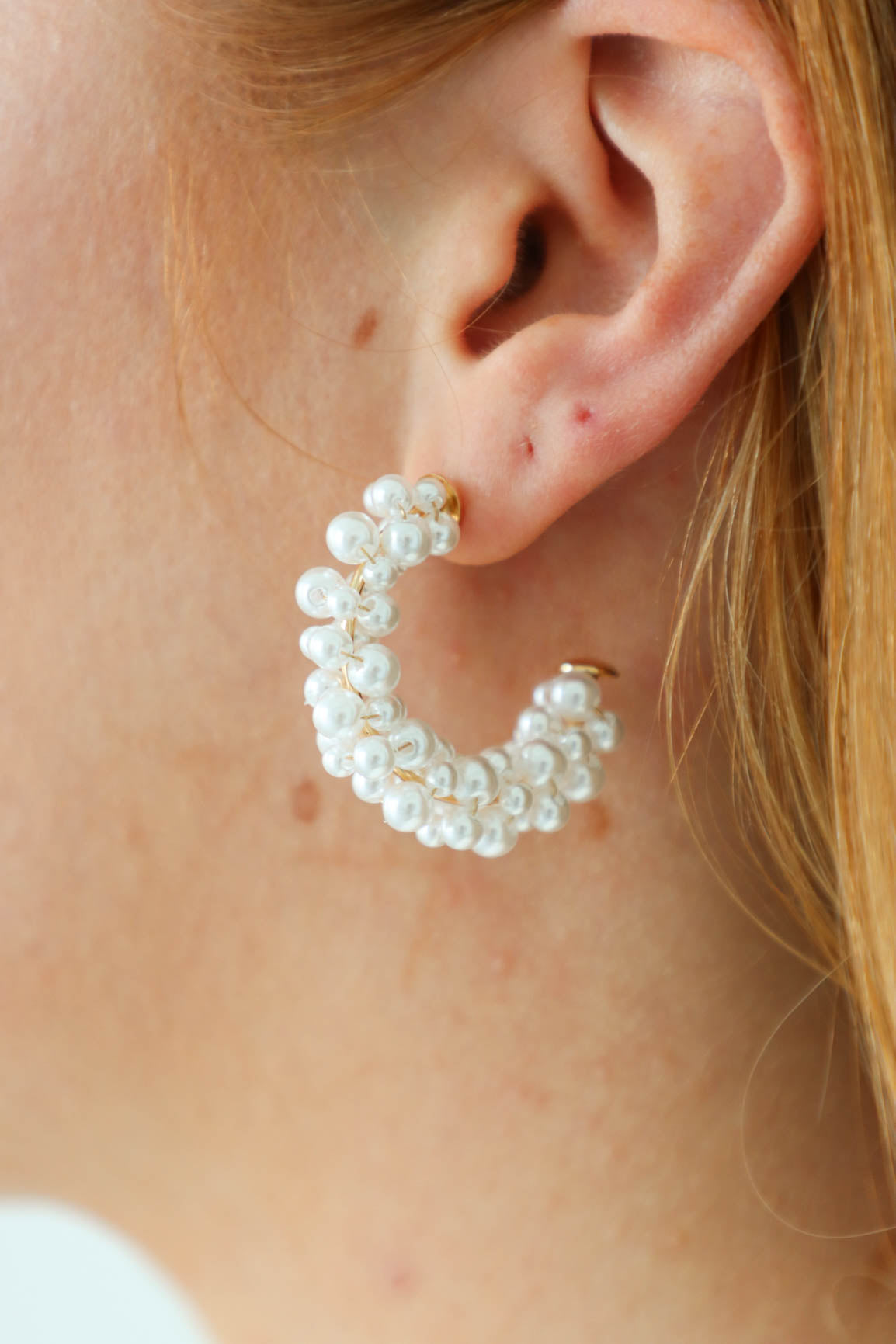 girl wearing white pearl hoop earrings