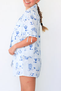 Woman wearing a blue and white patterned shirt with a plain background