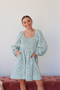 Woman wearing a light blue floral dress against a plain background