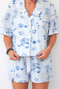 Person wearing a white outfit with blue animal print on a plain background