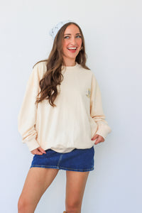 Woman wearing a cream sweater and blue denim skirt against a white background