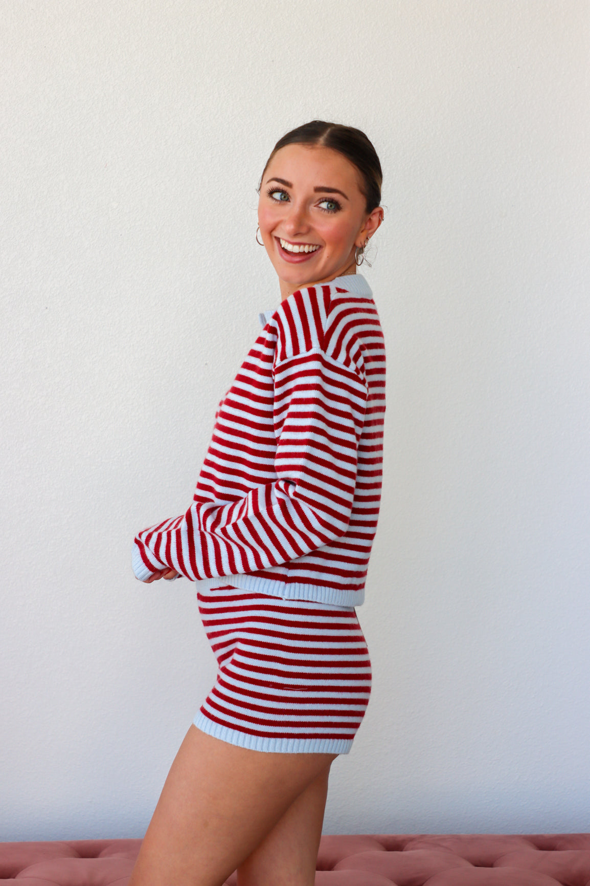 Woman wearing a red and white striped outfit against a plain background