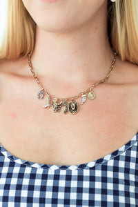 Necklace with charms worn by a person, visible above a blue and white checkered garment.
