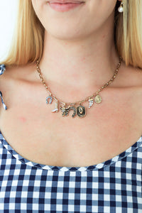 Necklace with charms worn by a person in a blue and white checkered dress.