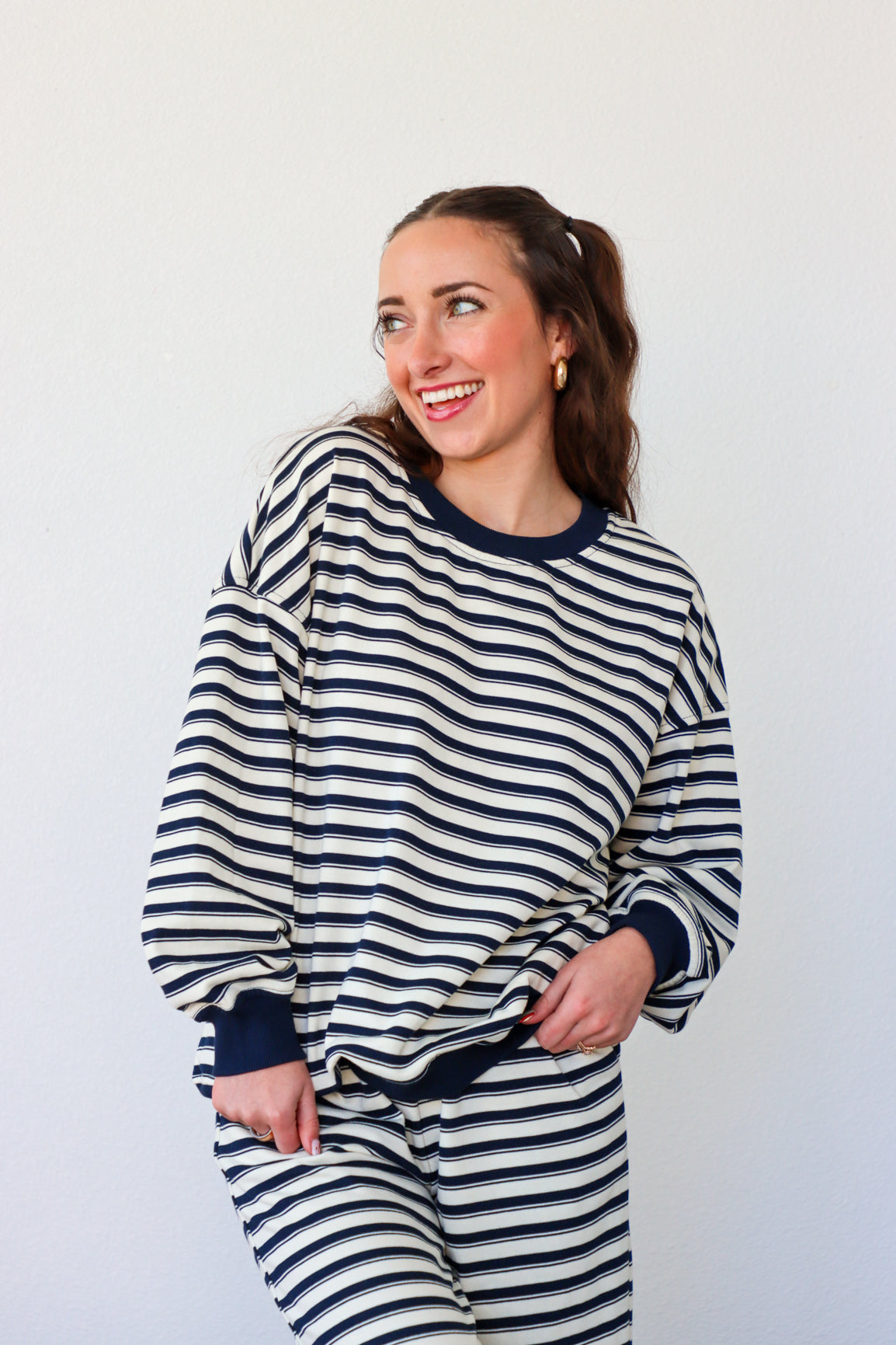 Woman wearing a navy and white striped outfit against a plain background