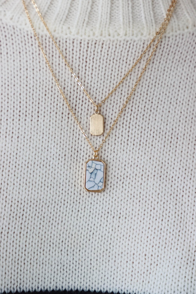 gold layered necklace with a white marble pendant charm
