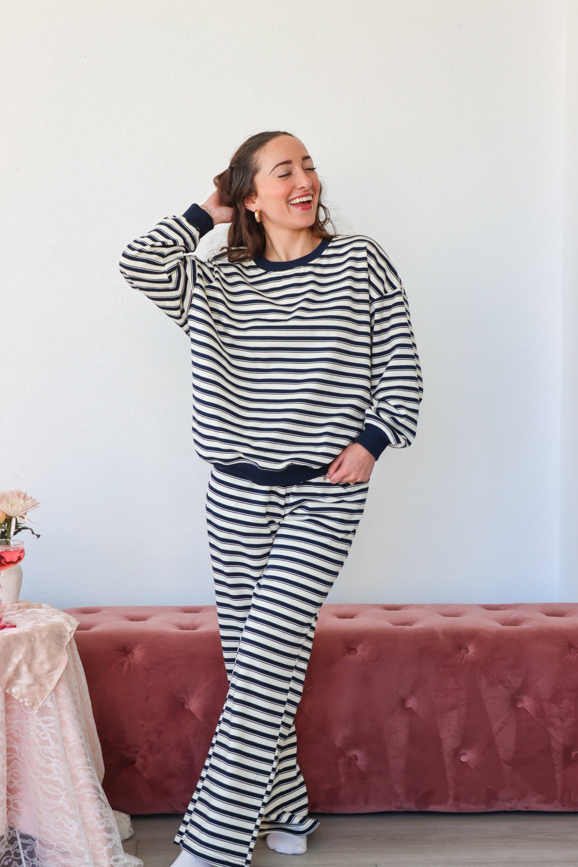 Woman wearing a black and white striped outfit standing in a room with a pink couch and table.