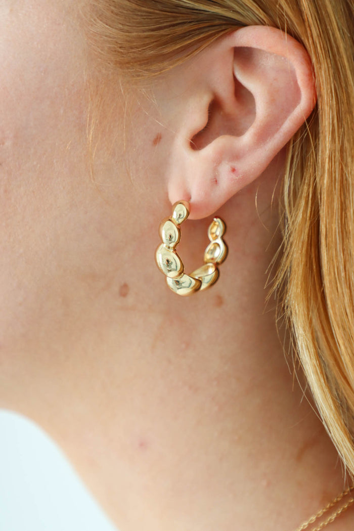 girl wearing gold scalloped hoop earrings