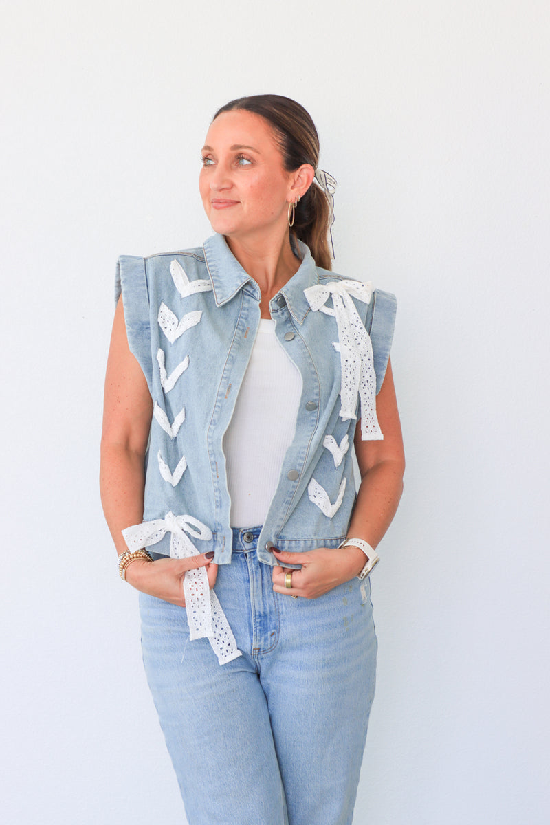 Woman wearing a light blue denim vest with lace details on a white background
