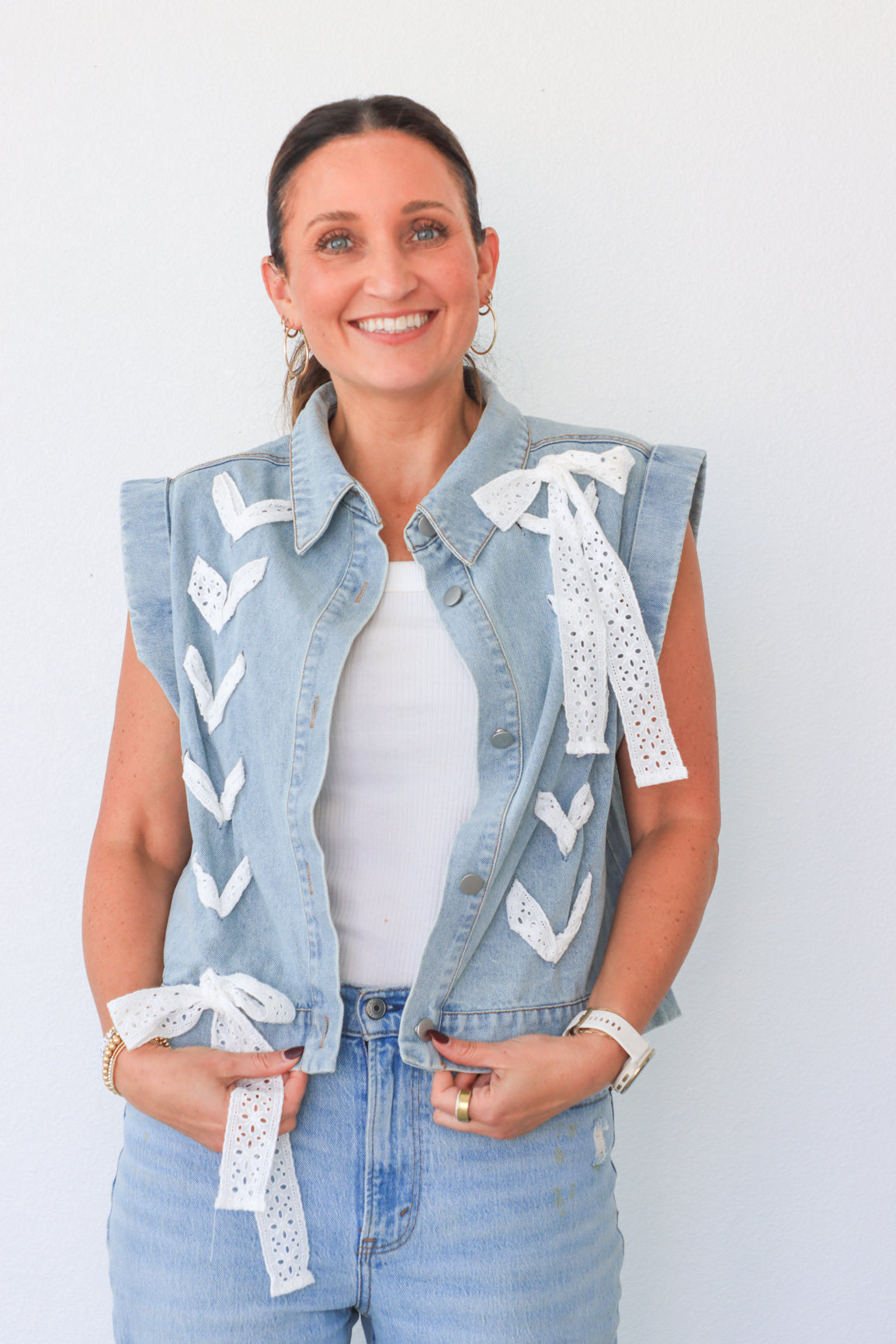 Woman wearing a denim vest with lace details on a white background