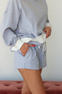 Person wearing a blue and white striped outfit with shorts, standing against a plain background.