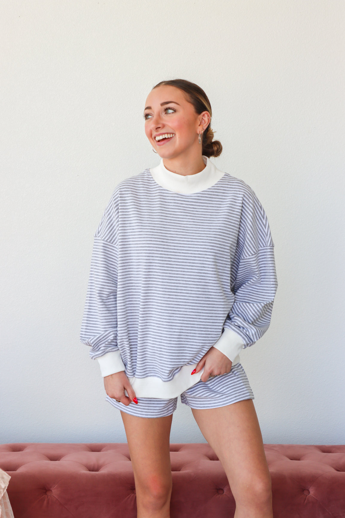 Woman wearing a striped sweater and shorts, standing against a plain background