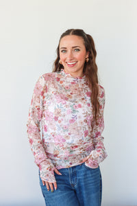 Woman wearing a floral blouse and blue jeans against a white background