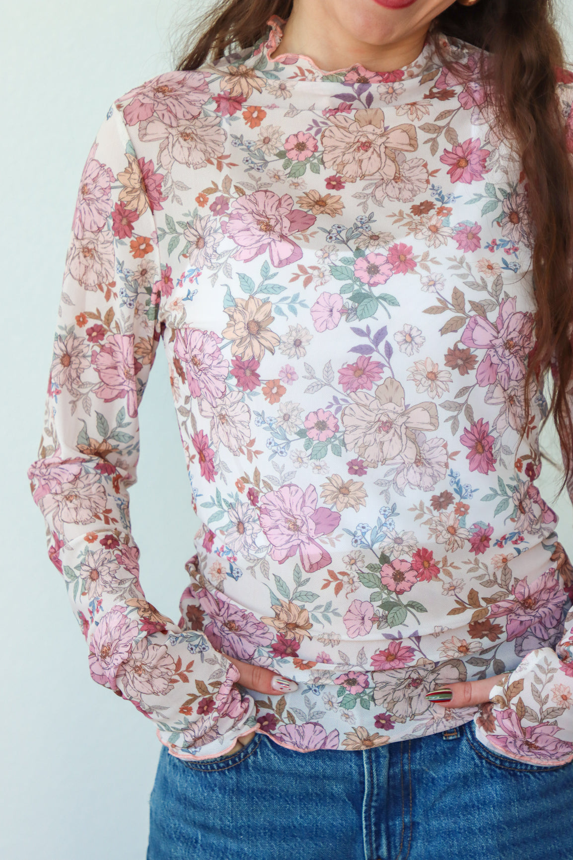 Person wearing a floral long-sleeve top with a plain background
