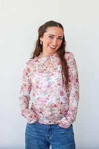 Woman wearing a floral blouse and blue jeans against a white background