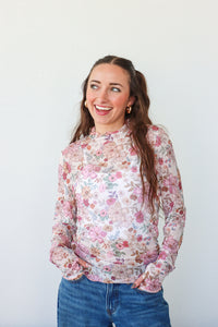 Woman wearing a floral blouse and blue jeans against a white background
