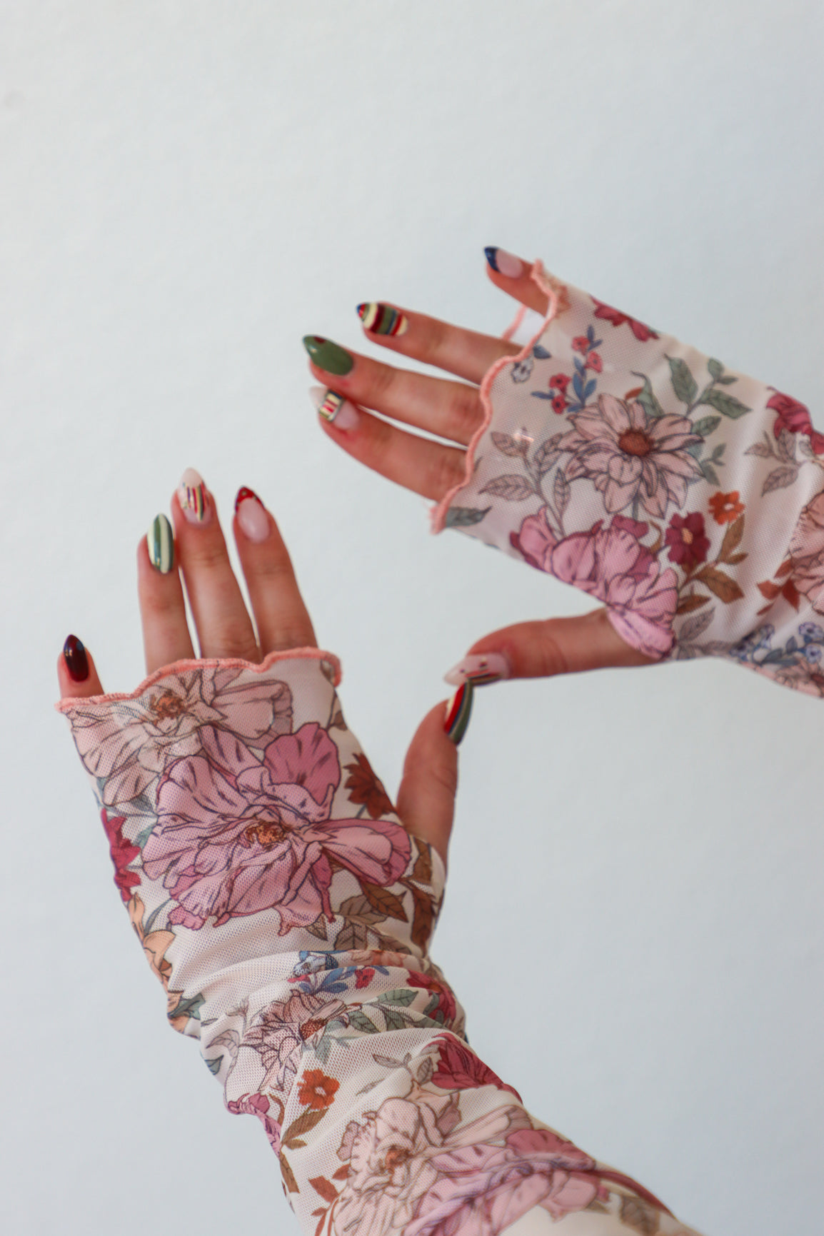 Floral patterned gloves worn on a white background