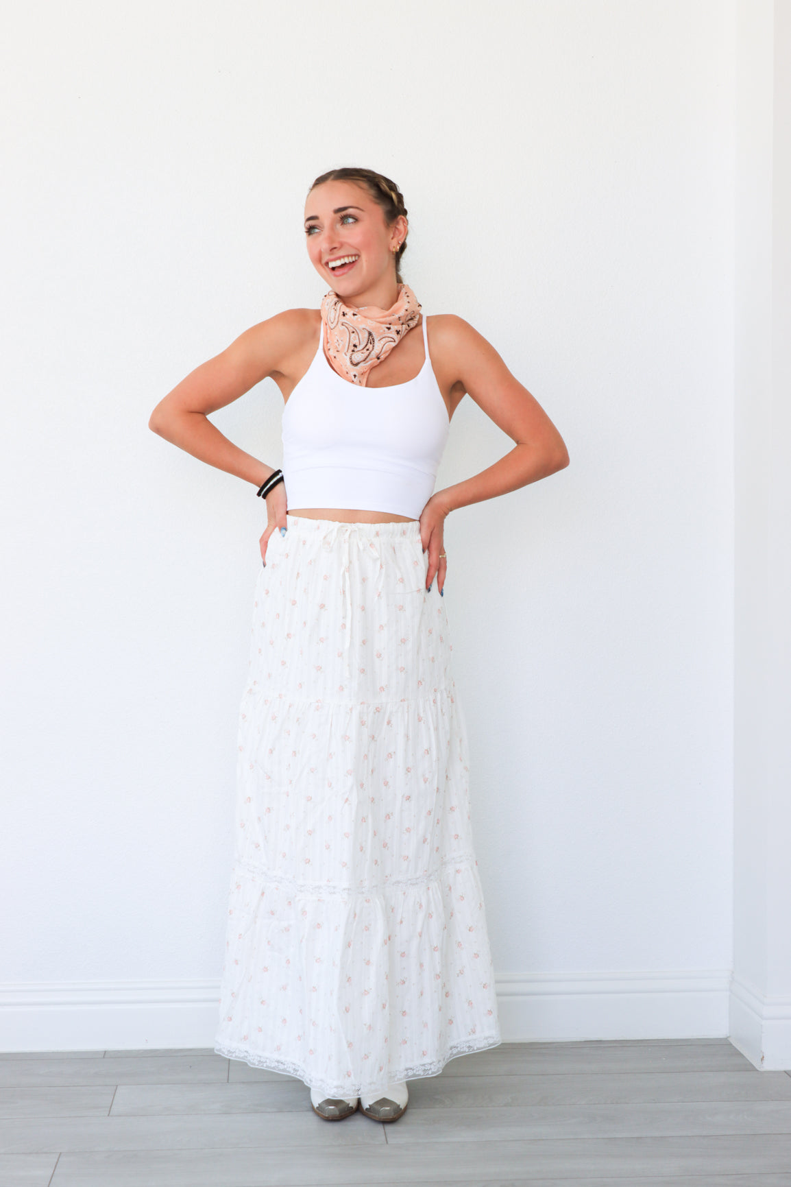 Woman wearing a white dress with a pink scarf in a minimal indoor setting