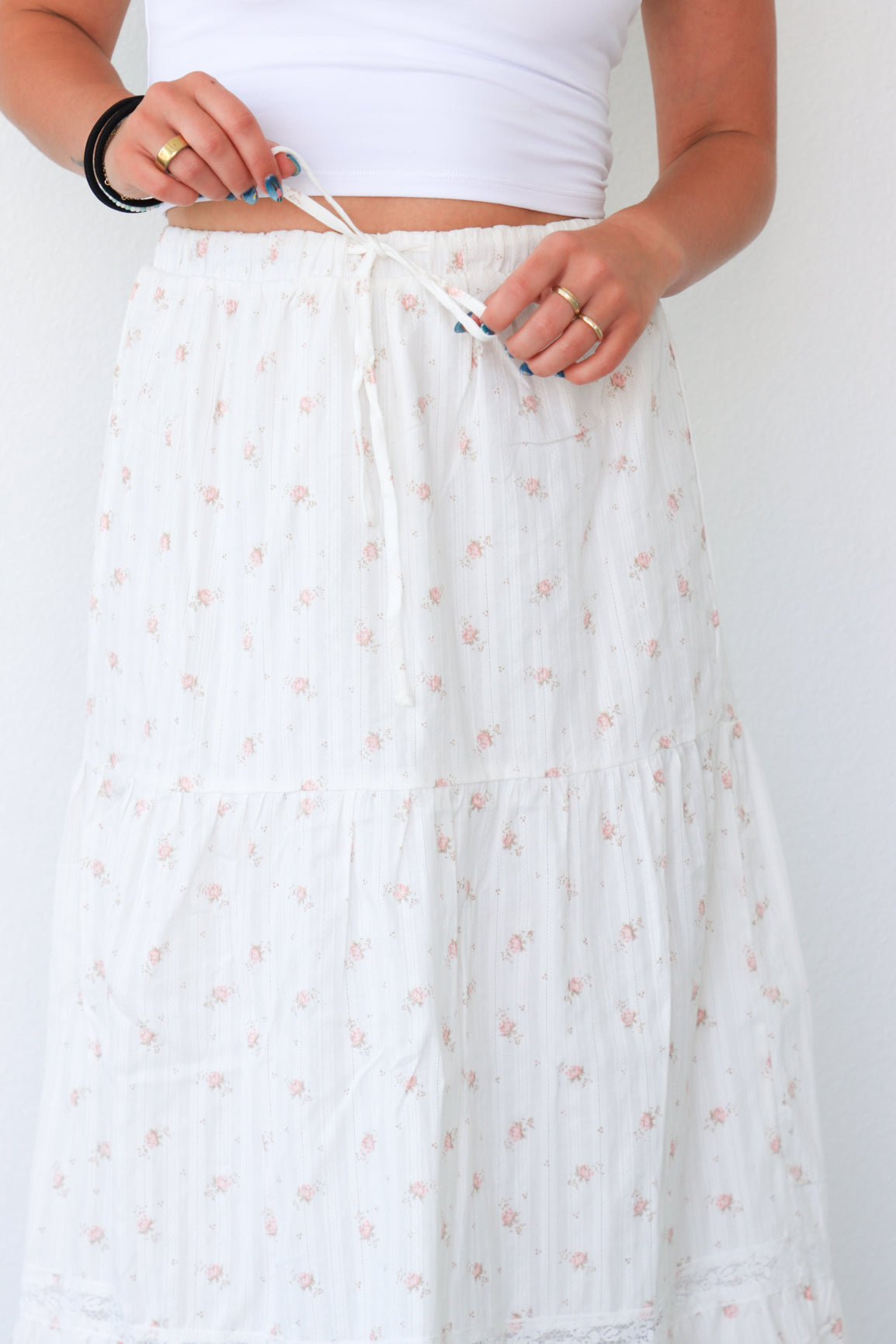 Person wearing a white skirt with a subtle pattern on a plain background