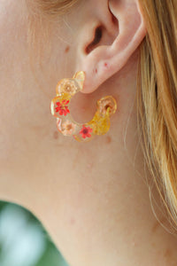 girl wearing resin hoop earrings with red flowers