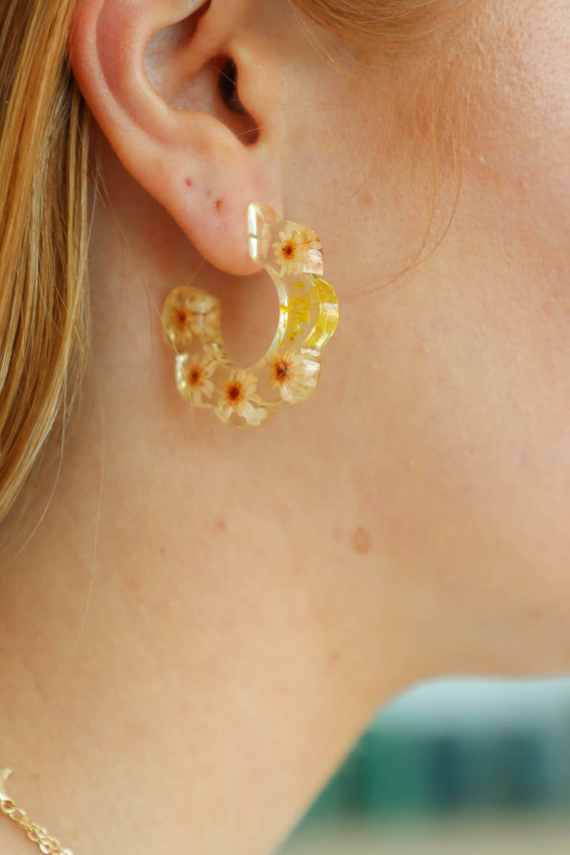 girl wearing resin hoop earrings with yellow flowers