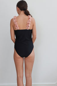 girl wearing black one piece swimsuit with pink floral straps