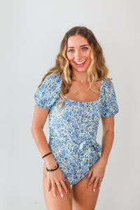 girl wearing blue floral cap sleeve one piece swimsuit