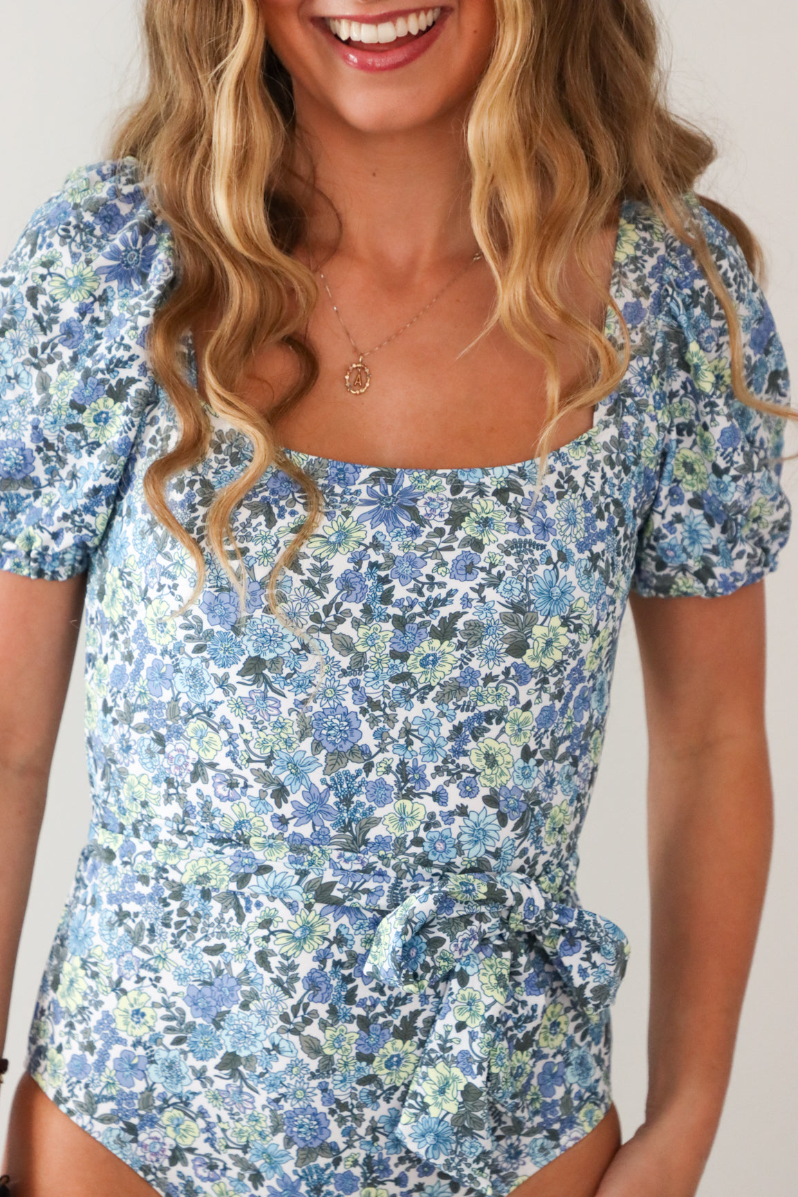 girl wearing blue floral cap sleeve one piece swimsuit