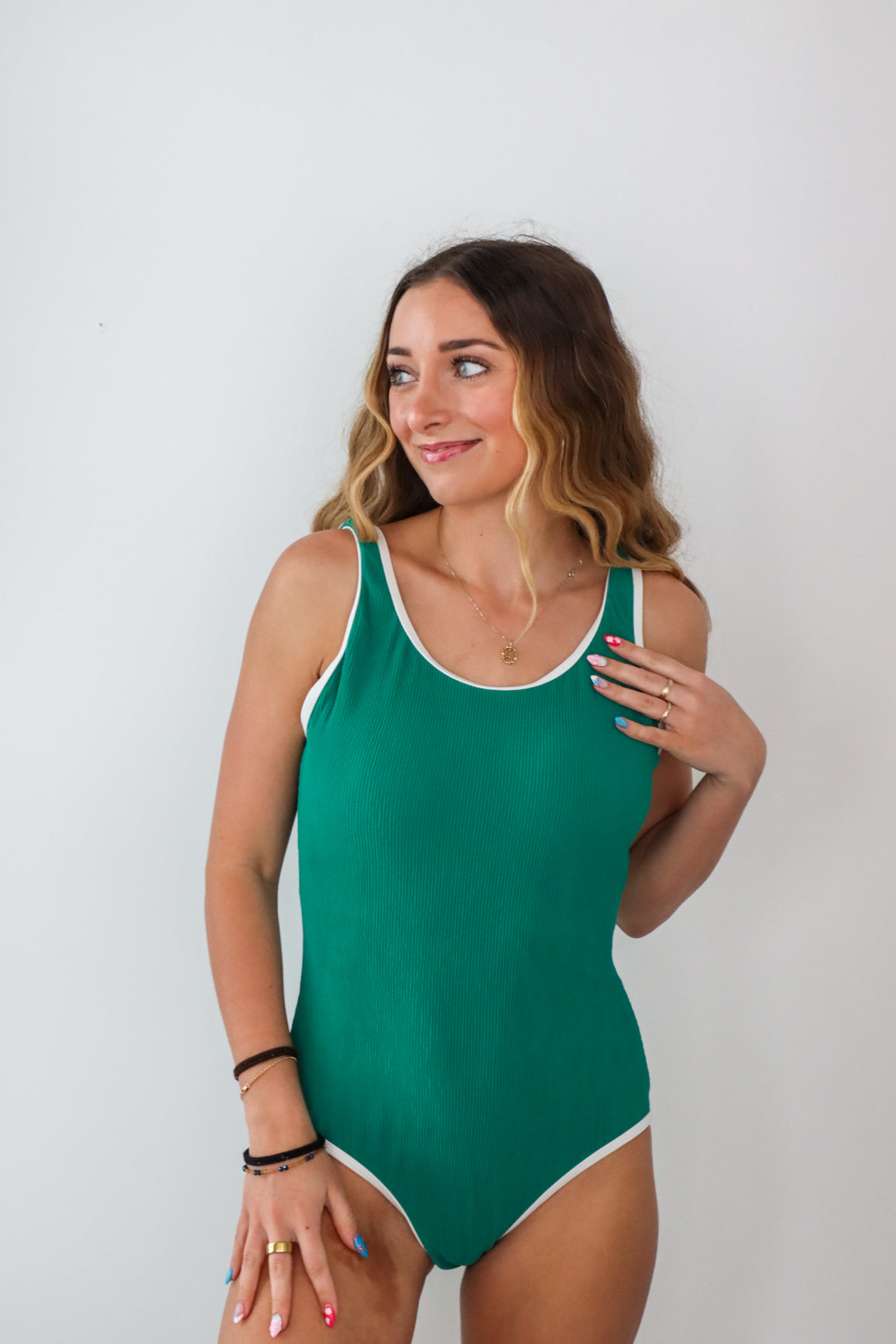 Woman wearing a green swimsuit against a plain background