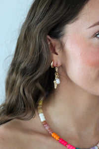 Close-up of a person wearing gold earrings with a blurred background
