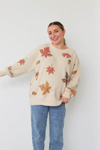 girl wearing cream sweater with leaf pattern