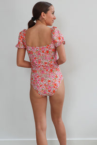 girl wearing pink floral one piece with puff sleeves