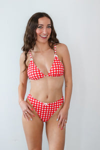 Woman wearing a red and white checkered bikini against a plain background