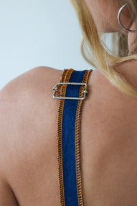 Close-up of a person wearing a blue and orange strap over their shoulder against a white background