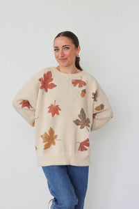 girl wearing cream sweater with leaf pattern