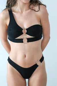 Black bikini with circular design on a plain background