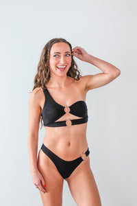 Woman wearing a black bikini against a light gray background