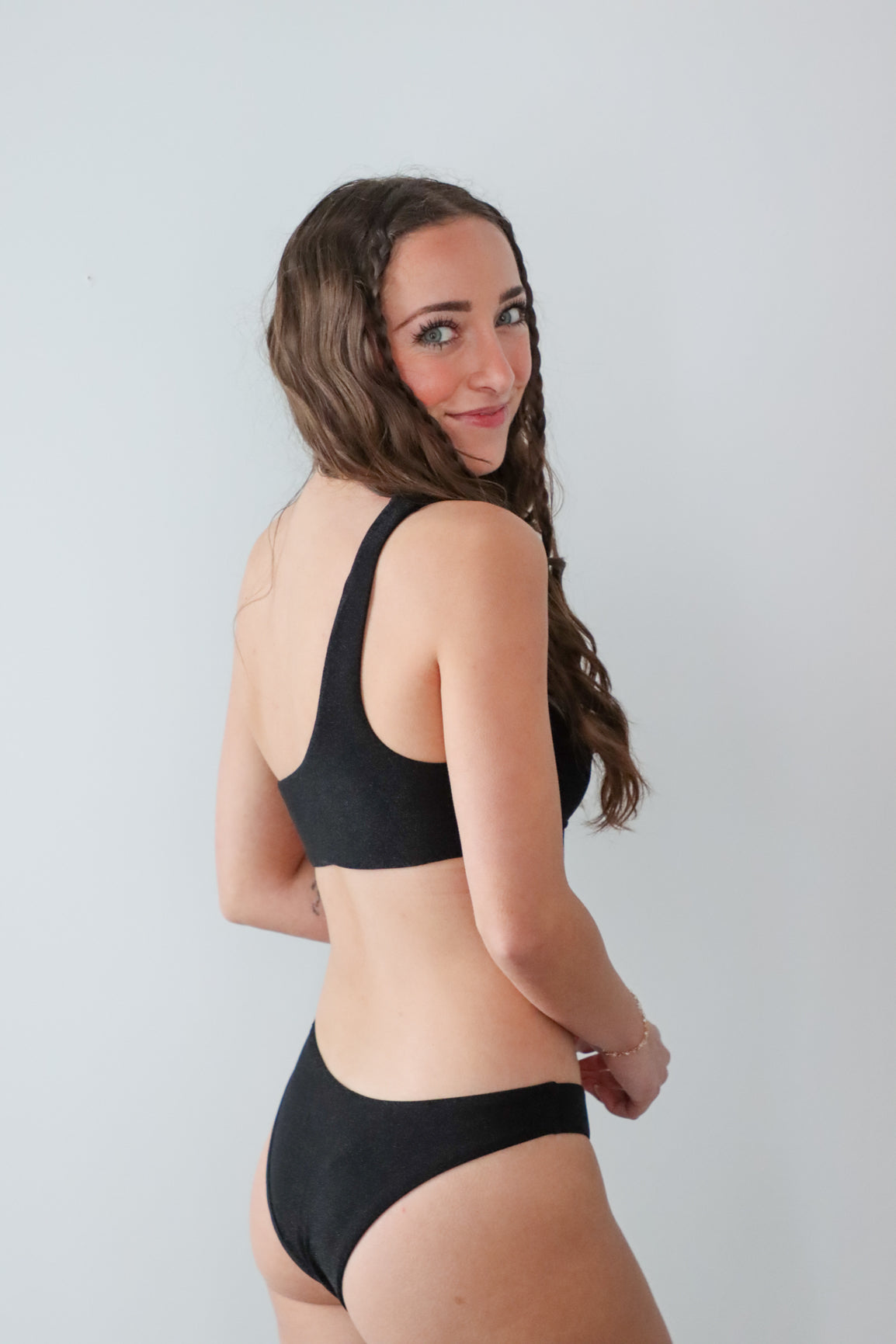 Woman wearing a black bikini against a plain background