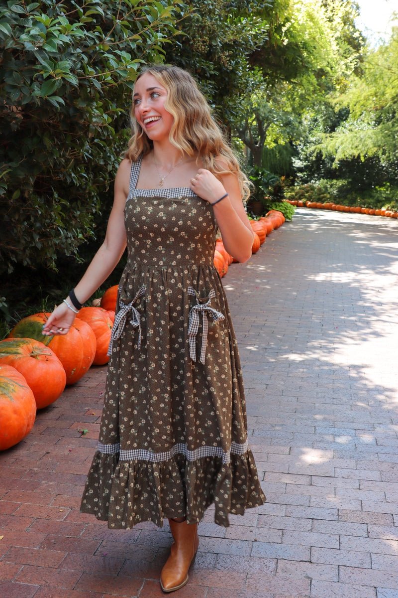 Woman in a polka dot dress standing among pumpkins in a pumpkin patch.