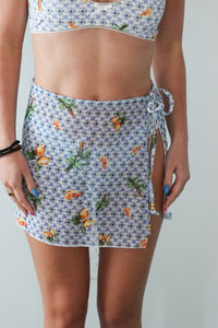 Person wearing a floral skirt and top on a plain background