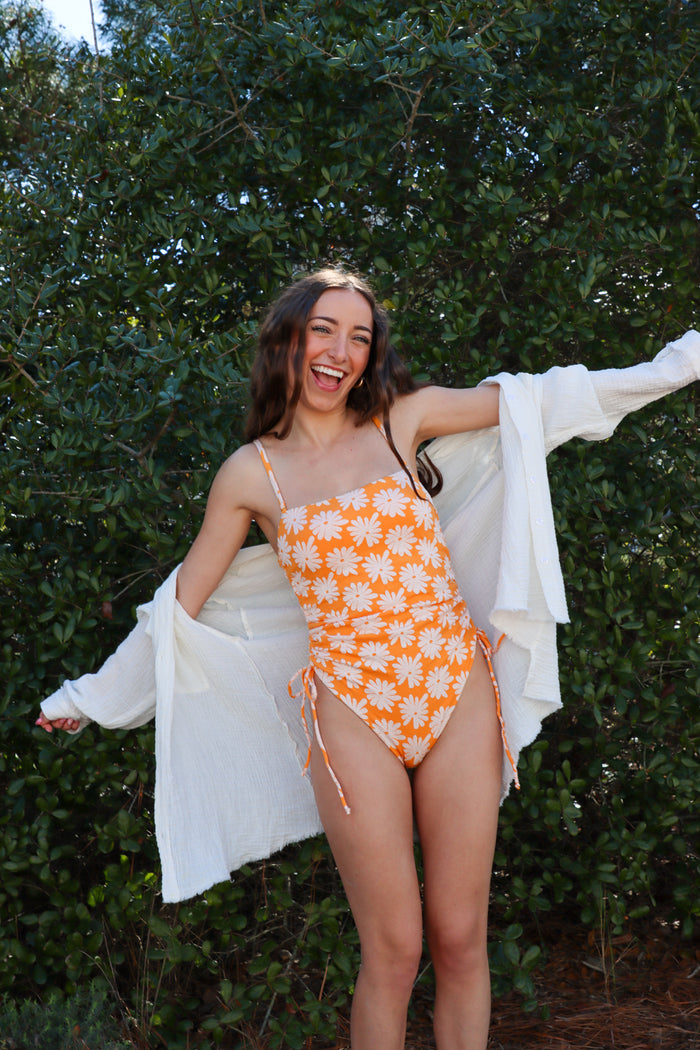 girl wearing orange floral one piece swimsuit