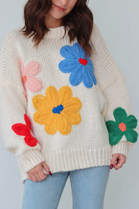 girl wearing cream sweater with large colorful embroidered flower detailing