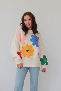 girl wearing cream sweater with large colorful embroidered flower detailing