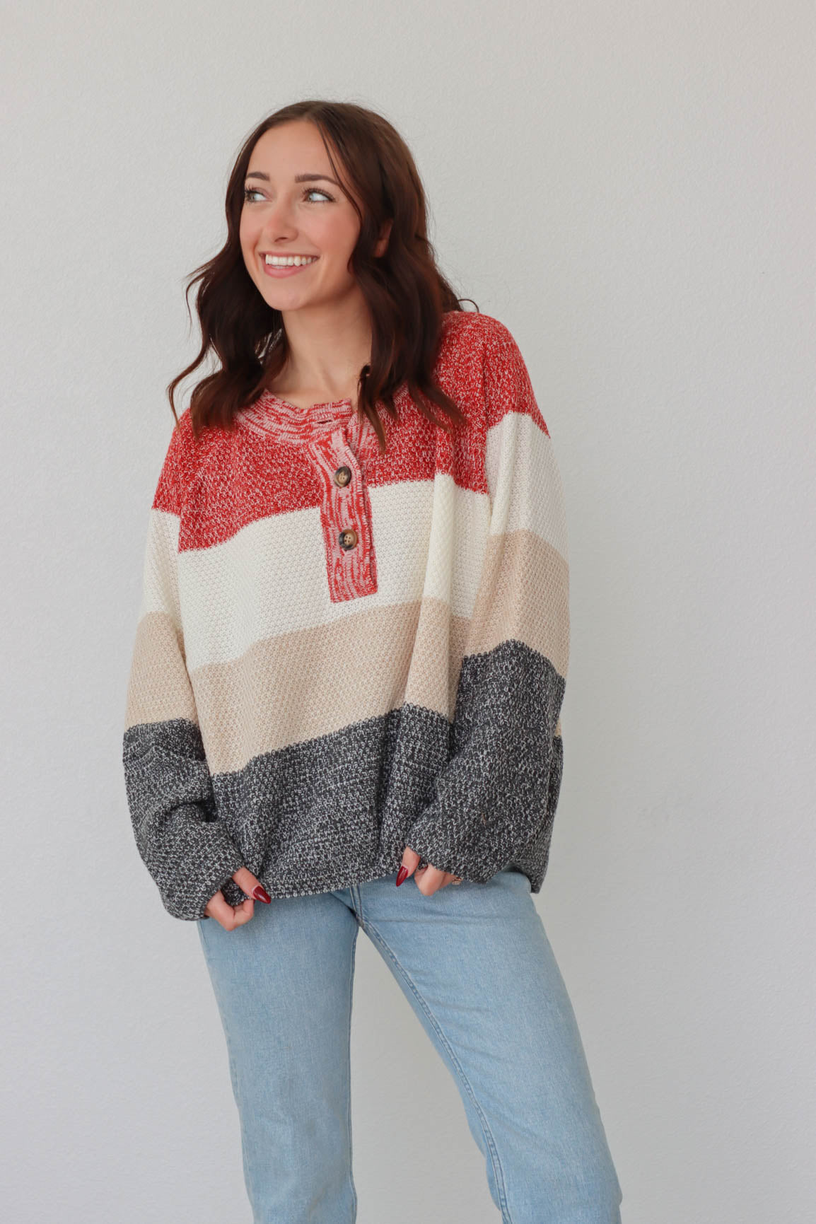girl wearing red, cream, and gray knit long sleeved top