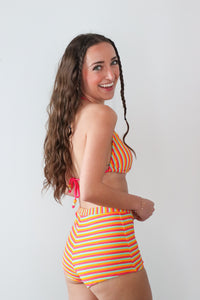 Woman wearing a colorful striped bikini against a white background