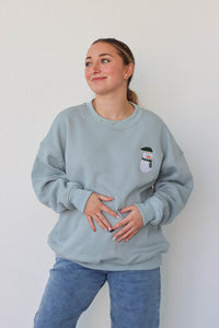 girl wearing light blue snowman crewneck